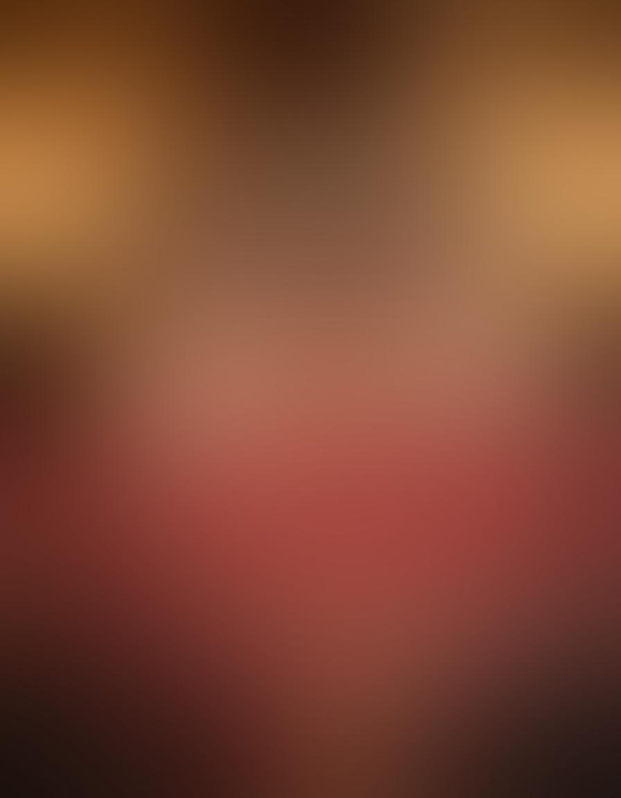 A serene bedroom setting illuminated by soft candlelight, featuring a beautifully adorned bed with silk sheets, surrounded by scattered rose petals. In the foreground, a couple sharing a tender moment, gazing into each other's eyes, embodying intimacy and warmth. Subtle hints of artful decorations enhancing the sensual atmosphere. soft focus. warm colors. painting.